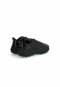 Scarpe nere senza lacci con suola in gomma testurizzata, caratterizzate da motivi ondulati e linguette posteriori per una facile calzata.