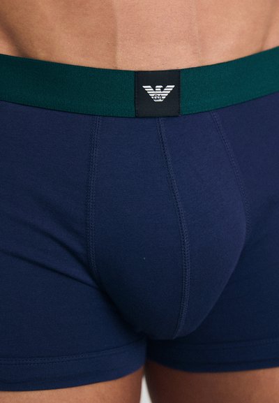 Mørkeblå boxershorts med grønt elastisk liv, med et logo-lap, laget av et mykt bomullsblandingsstoff.