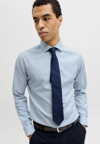 Heleroheline triibuline triiksärk krae ja pikkade varrukatega, sobitatud tumelilla lipsuga. Kangal on siledapind.