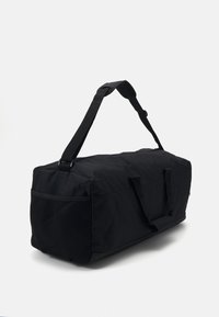 Geantă duffel neagră, made dintr-un material durabil, având o formă rectangulară, curea de umăr ajustabilă și un panou din plasă pe o parte.