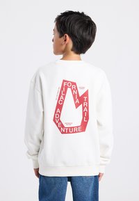 Valkoinen huppari, jossa on kuusikulmainen punainen graafinen painatus selässä. Siinä on tekstit "California Trail Adventure" ja "Inspired by Nature."