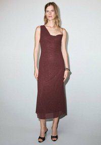 Bordový, jednoramenný midi šaty s priliehavým strihom a jemnou trblietavou textúrou. Skombinované s čiernymi sandálmi na viazanie.