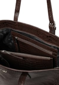 Brun handväska med krokodilmönster, invändigt med flera fickor med dragkedja och ett mönstrat foder. Mjuk läderstruktur, hållbar design.