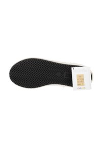 Suela de goma negra con un patrón de espiga, borde superior liso, etiqueta adjunta que muestra la marca y los íconos, paleta de colores general apagada.