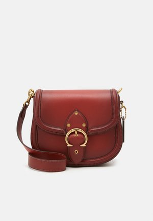 Sac bandoulière en cuir marron avec boucle dorée sur le rabat avant et bandoulière réglable sur fond blanc.