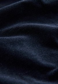 Tumši jūras zilas audums ar teksturētu, rievotu rakstu, kurā ir mīksti, viļņaini salocījumi, kas izceļ tā kokvilnas vai kordūras īpašības.