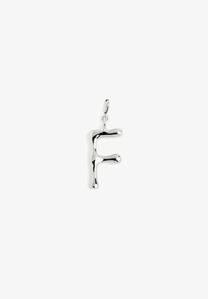 Pendentif en métal argenté en forme de lettre "F", avec un design organique et lisse, aux bords arrondis et à la finition polie.