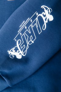 Felpa blu navy con una texture morbida che presenta un testo grafico bianco e un design di scimmia. Il testo riporta "ULTRA" e "REBEL" in un carattere stilizzato.
