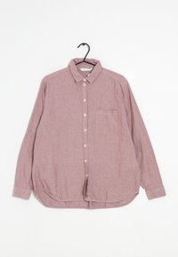 Camisa de manga larga color óxido hecha de tejido texturizado, con botón en la parte frontal, bolsillo y dobladillo redondeado.