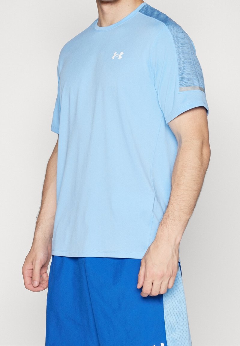 Ljusblå atletisk t-shirt med korta ärmar, med en texturerad blå panel på axeln och en vit logo på bröstet.