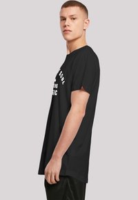 Black short-sleeve t-shirt with a relaxed fit. Features white text on the front. Smooth cotton fabric with a minimalist design.