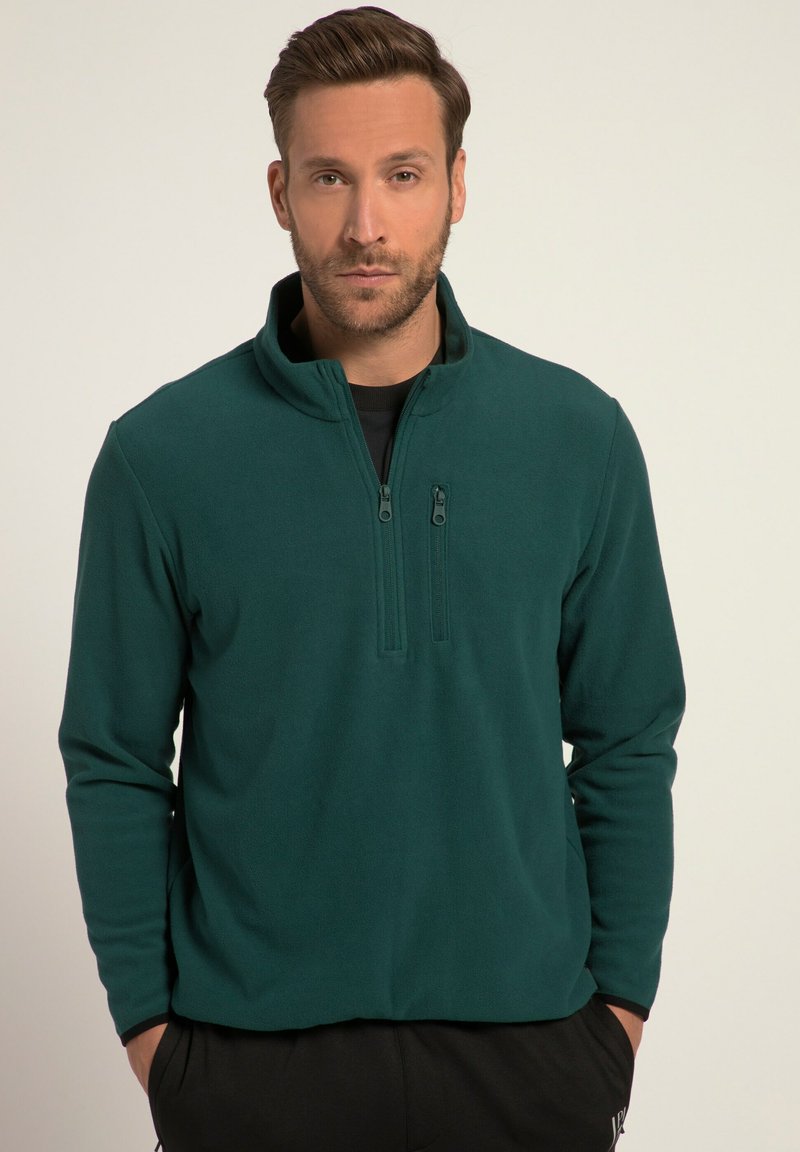 Pullover in pile verde scuro con colletto a mezza zip, maniche lunghe e una texture morbida. Presenta due tasche con zip sul davanti.