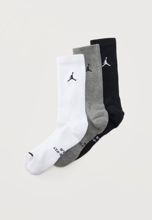 Trois paires de chaussettes mi-mollet en blanc, gris et noir avec un petit logo Jumpman et des marquages de taille sur la zone du pied.
