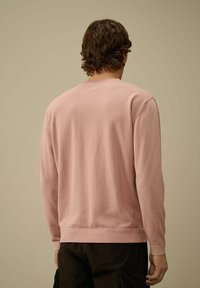 Felpa a maniche lunghe in cotone rosa chiaro, con collo rotondo e polsini a costine, caratterizzata da una texture morbida e un design semplice.