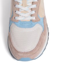 Zapatilla ligera que combina gamuza beige y acentos azules, con una caja de dedos de malla y cordones blancos planos. Suela gris sólida.