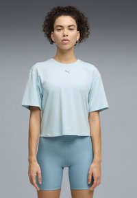 Ανοιχτό μπλε κοντομάνικο κοντό μπλουζάκι με στρογγυλή λαιμόκοψη, με μικρό λογότυπο στο στήθος. Συνδυάζεται με εφαρμοστά σορτς στο ίδιο μπλε χρώμα.