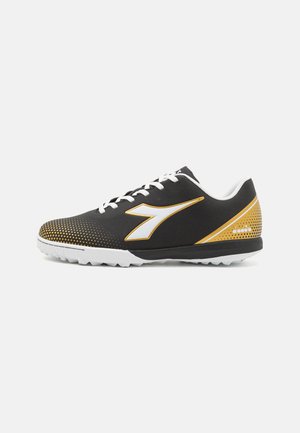 Scarpa sportiva nera con tomaia texturizzata, lacci bianchi, dettagli dorati e suola bianca. Presenta un motivo a pois e un logo laterale.