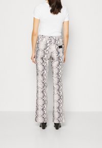 Pantalones acampanados ajustados con un patrón de serpiente, que presenta tonos de gris y blanco. El material tiene una textura suave con una pequeña etiqueta negra en la parte posterior.