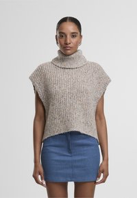 Kreemjas lõngakootud kõrge kaelusega sviiter, millel on tekstureeritud soonikmuster ja lühikesed varrukad, koos teksamini seelikuga.