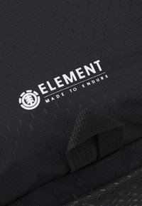Tissu noir texturé avec le logo et le slogan de la marque Element "Made to Endure" en blanc, avec une petite boucle en tissu sous le texte.