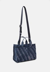 Blauwe canvas tote met een gradient patroon, voorzien van twee handvatten bovenaan, een afneembare verstelbare schouderband en een zilveren accenten. Textuurafwerking.