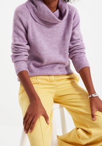 Pull en tricot lavande avec un col bénitier et des poignets côtelés, associé à un pantalon en velours côtelé jaune pâle. Texture lisse, coupe décontractée.