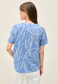 Camicia blu a maniche corte con motivo a foglie bianche, con scollatura rotonda e vestibilità rilassata. Tessuto morbido con superficie liscia.