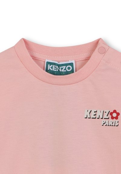 Różowa bawełniana koszulka z okrągłym dekoltem, zapięciem na napy oraz grafiką "KENZO PARIS" z akcentem kwiatowym w kolorze czerwonym i zielonym.