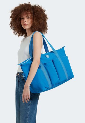 Blue tote bag made of durable fabric, featuring three front pockets, textured straps, and a zipper closure.