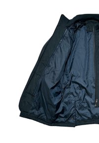 Giacca isolante blu navy con zip frontale, colletto a costine e fodera interna liscia. Presenta una vestibilità su misura con tasche laterali.