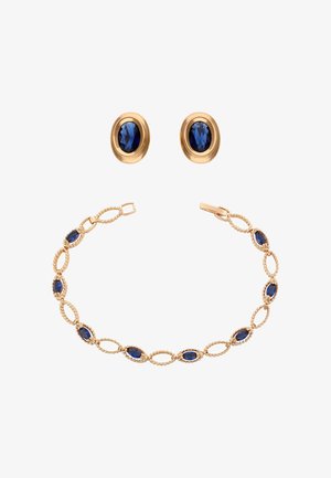 Złote kolczyki i pasująca bransoletka z owalnymi, niebieskimi kamieniami szlachetnymi osadzonymi w misternym, połączonym wzorze na białym tle.