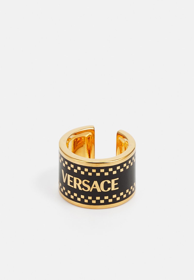 Guld-tone cuff ring med en sort band, der har "VERSACE"-logoet og et ternet mønster langs kanten. Glat overfladefinish.