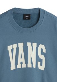 Sweat-shirt à col rond bleu avec un grand texte blanc "VANS" sur le devant et une étiquette de la marque Vans à l'intérieur du col, taille petite.