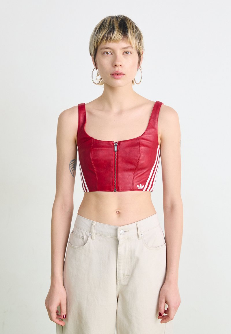 Top curto vermelho feito de couro com fecho frontal em zíper, apresentando riscas verticais brancas nas laterais e um detalhe em logótipo bordado.