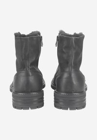 Bottes chelsea noires en cuir avec une finition texturée, dotées d'une doublure en shearling, de semelles en caoutchouc plates et de fermetures éclair sur le côté pour un enfilage facile.