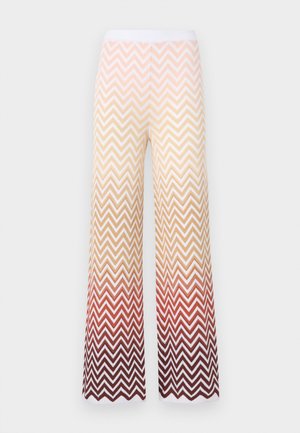 Vidbenade stickade byxor med ett zigzag chevron-mönster som övergår från krämfärg till orange och djupröd, med ett vitt elastiskt midjeband.