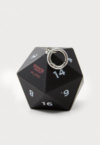 Melnā, ģeometriskā kauliņa formā veidota atslēgu piekariņa ar sudraba detaļām, kurā ir baltas ciparu un sarkans "Stranger Things" logotips.