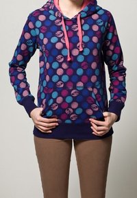Sweat à capuche avec un motif à pois bleu, rose et violet sur un fond bleu marine ; comprend une poche kangourou à l'avant et des cordons de serrage.