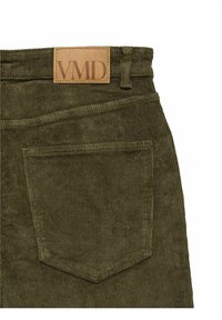 Olivgröna kordbyxor med en struktur av ribbor, som har en brun läderetikett med präglad "VMD" och en bakficka.