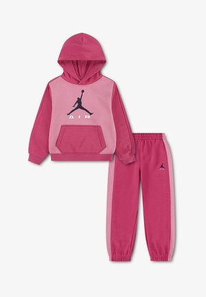 Różowy dwuczęściowy dziecięcy dres z bluzą z kapturem i spodniami dresowymi, oba z czarnym logo Jumpman i białym napisem "AIR".