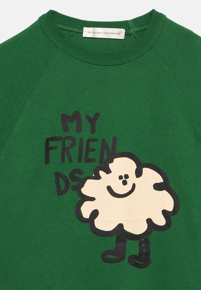 Maglietta verde con la scritta "MY FRIENDS" e una nuvola cartone sorridente con gambe stampata sotto lo scollo.
