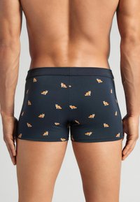 Boxers para hombre en tela azul marino oscuro con pequeños patrones de zorros naranjas. Cintura elástica. Textura suave, diseño ajustado y cobertura hasta medio muslo.