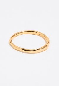 Pulsera de brazalete color oro con una superficie suave y ondulada, que presenta un diseño sin juntas y un acabado pulido.