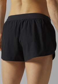 Svarta träningsshorts med elastisk midja, som har en lös passform och en något rundad fåll för ökad rörlighet.