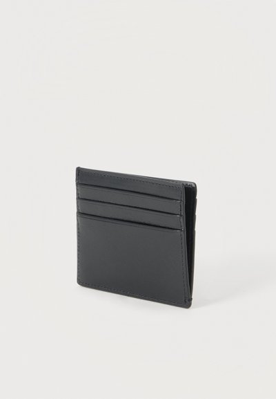 Petit portefeuille en cuir noir avec trois emplacements horizontaux pour cartes et une poche plus grande, debout sur un fond blanc uni.