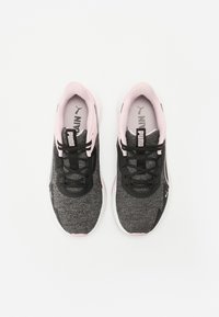 Baskets de sport noires et roses avec un dessus texturé, des lacets plats et une semelle rembourrée. Présentent un logo sur la languette et un design épuré.
