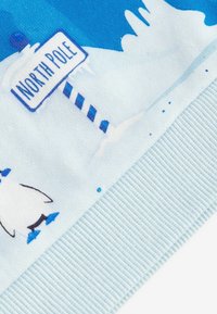 Tessuto azzurro chiaro con un pinguino e un cartello "Polo Nord", con un orlo a coste testurizzato e sottili decorazioni di neve bianca e accenti blu.