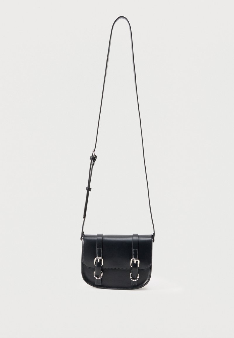 Μαύρη δερμάτινη τσάντα ώμου με ρυθμιζόμενο λουρί και δύο ασημένιες αγκράφες κλεισίματος στο μπροστινό καπάκι, σε λευκό φόντο.