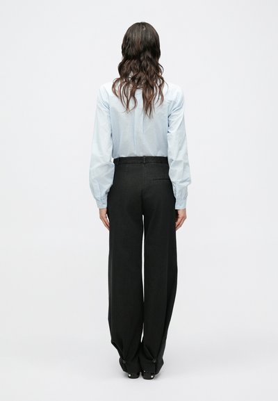 Blusa azul claro a rayas con mangas abullonadas, combinada con pantalones negros de pierna ancha de talle alto. Diseño sencillo, corte entallado, sin patrones visibles.