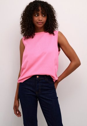 Mouwloze roze gebreide top met een ronde halslijn, gecombineerd met donkerblauwe jeans. De top heeft een ontspannen pasvorm en een gladde textuur.